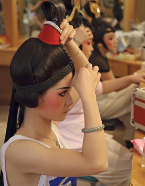 Chinese opera actress painting face at backstage