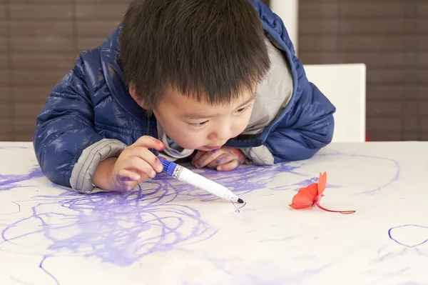 Et søtt barn maler på bordet. – stockfoto