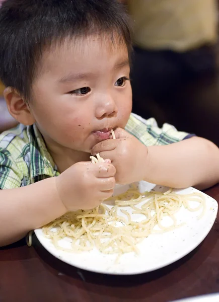 Baby essen, um nach Nudeln zu greifen — Stockfoto