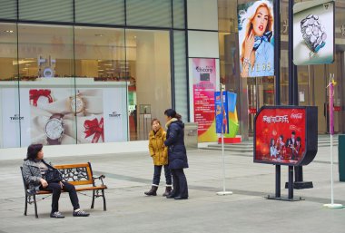 yoğun bir yaya alışveriş caddesi üzerinde bir sandalyede oturan kadın