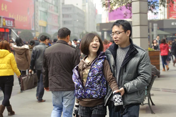 Una giovane coppia passa attraverso una trafficata via pedonale dello shopping — Foto Stock