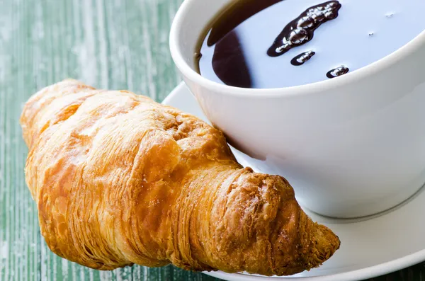 Cofee und Croissant auf grünem Tisch — Stockfoto