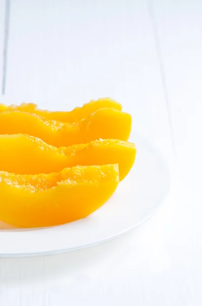 Scheiben Pfirsich in Dosen auf weißem Tisch — Stockfoto