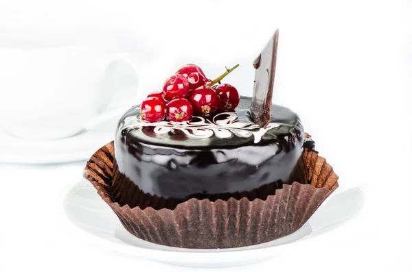 Schokoladenkuchen mit roten Johannisbeeren und weißer Tasse — Stockfoto