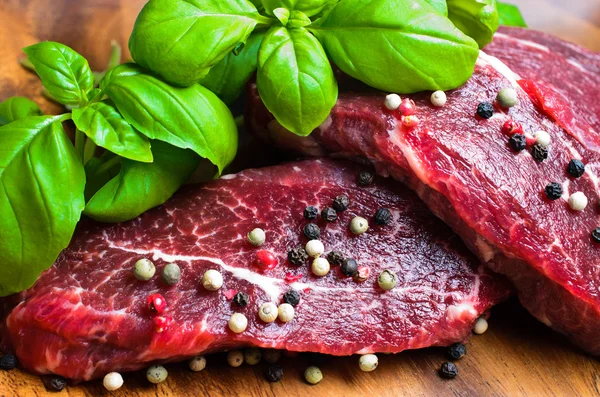 Hovězí steak na dřevěné desce s bazalkou — Stock fotografie