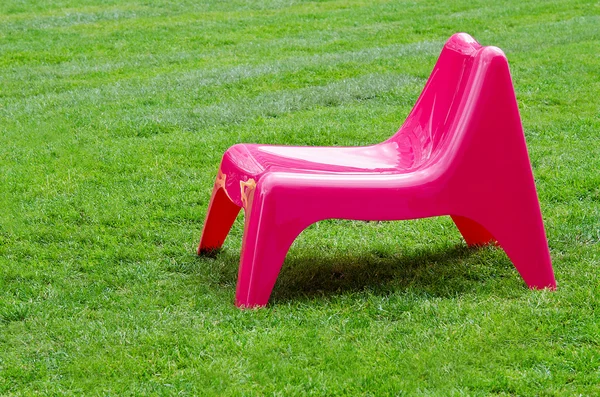 Розовое кресло на зеленой траве — стоковое фото