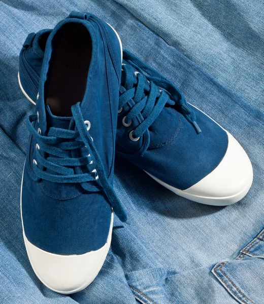 Een paar nieuwe blauwe schoenen op een jeans — Stockfoto