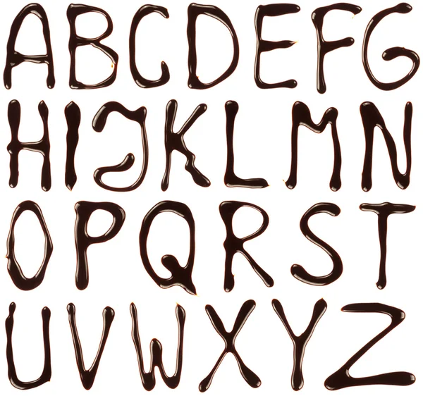 Алфавитные буквы, написанные шоколадным сиропом на белом фоне — стоковое фото