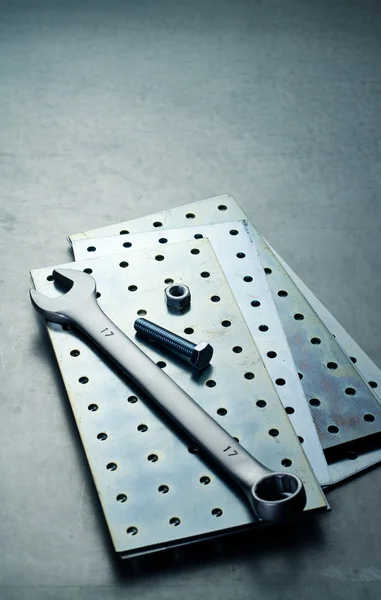 Wrench, nut and screw on a metal plate — Stock Photo, Image