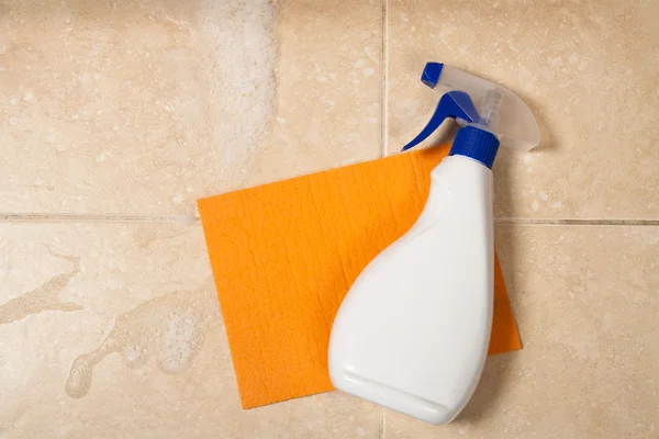 Spray bottle is on a orange sponge and tile — Stock Photo, Image