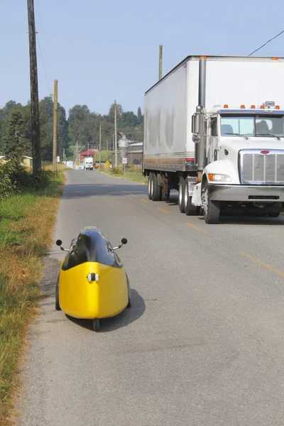 Ένα velomobile ή ποδήλατο αυτοκίνητο περνάει ένα φορτηγό — Φωτογραφία Αρχείου