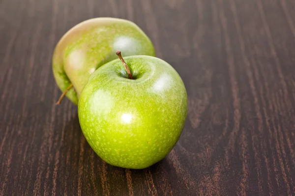 Deux pommes sur une table en bois sombre — Photo