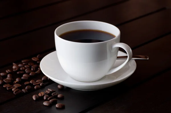 Café negro sobre mesa con grano de café —  Fotos de Stock
