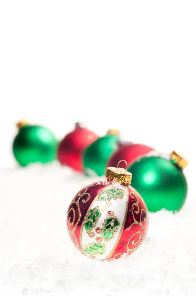 Красные, зеленые и красочные рождественские безделушки на снегу — стоковое фото