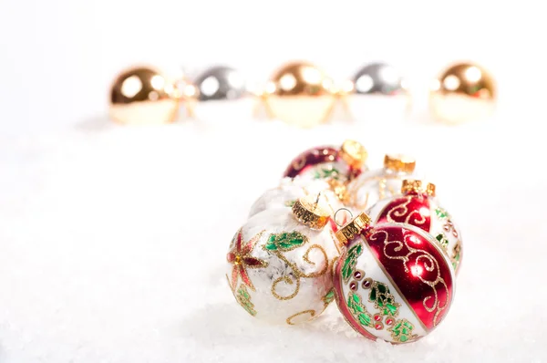 Christmas baubles on snow with gold and silver baubles in a line — Stock Photo, Image