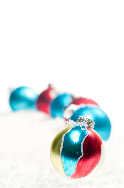 Красная, синяя и раскрашенная вручную рождественская безделушка на снегу — стоковое фото