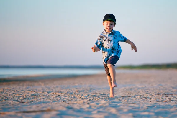 Kid körs på stranden vid solnedgången — Stockfoto