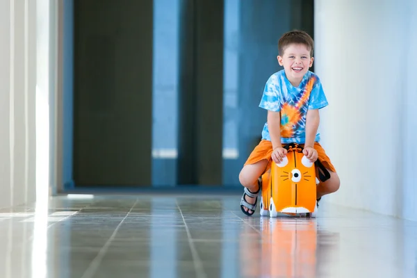 Carino ragazzo felice con una valigia in aeroporto — Foto Stock