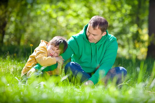 Bonito menino abraça seu pai ao ar livre — Fotografia de Stock