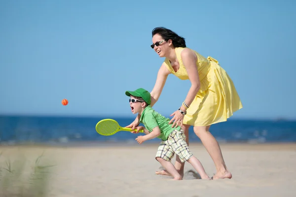 Jovem mãe e filho brincando na praia — Fotografia de Stock