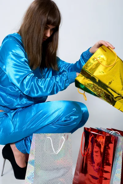 Meisje in blauwe kleren kijkt in een gouden pakket — Stockfoto
