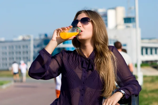 Girl in dark glasses drinks orange drink — Stock Photo, Image