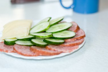 kesilmiş peynir, sosis ve bir tabak içinde salatalık