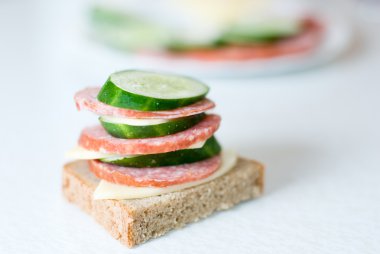 Sandwich with sausage, cheese and a cucumber clipart