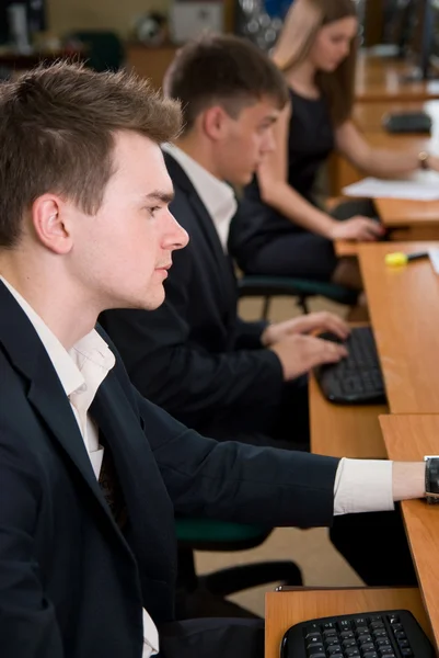 Young business sitting at a table, using computer when tr — Stock Photo, Image