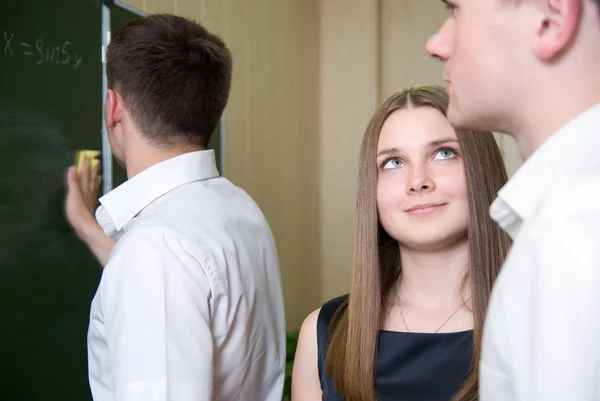 Young guy wipes a board, and girl looks at colleague — Stock Photo, Image