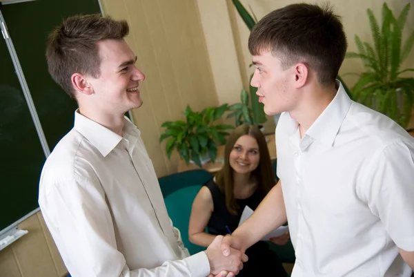 Два молодых улыбающихся человека пожимают друг другу руки — стоковое фото