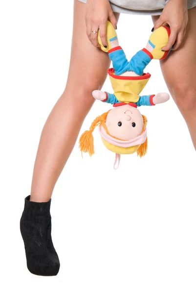 Puppe hängt an einer Hand an Mädchen zwischen den Füßen — Stockfoto