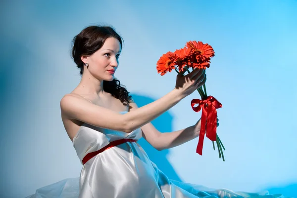 Gravid kvinna rymmer blommor på utsträckta armar — Stockfoto