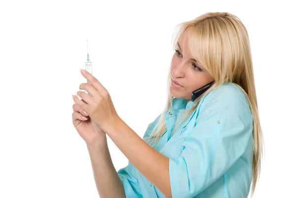 Doctor holds a syringe and speaks by phone — Stock Photo, Image