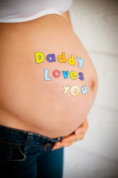 Красивая беременная модель ожидает новорожденного в джинсах и белом топе — стоковое фото