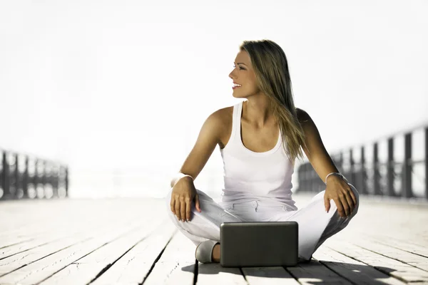 Young woman with a laptop on the pier — Stock Photo, Image