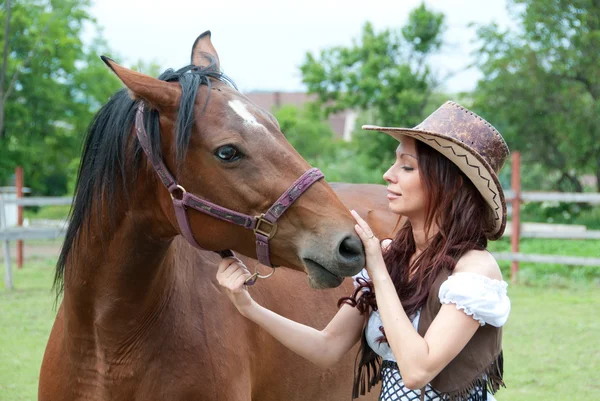 Красивая брюнетка гладит лошадь — стоковое фото