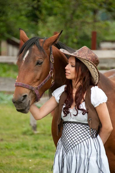 A beautiful girl in a cowboy hat with a horse — Stock Photo, Image