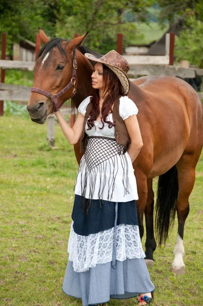 Une belle fille dans un chapeau de cow-boy avec un cheval — Photo