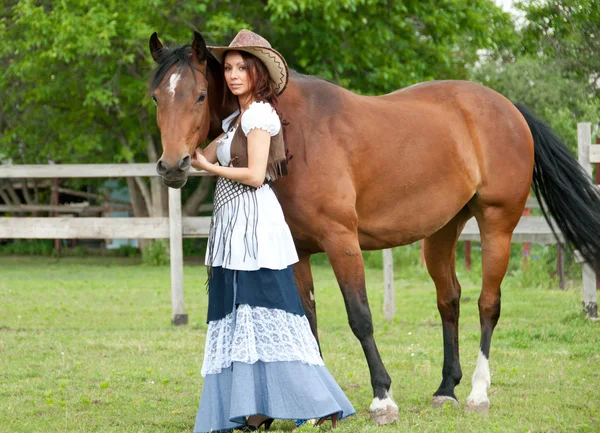 A beautiful girl in a cowboy hat with a horse — Stock Photo, Image