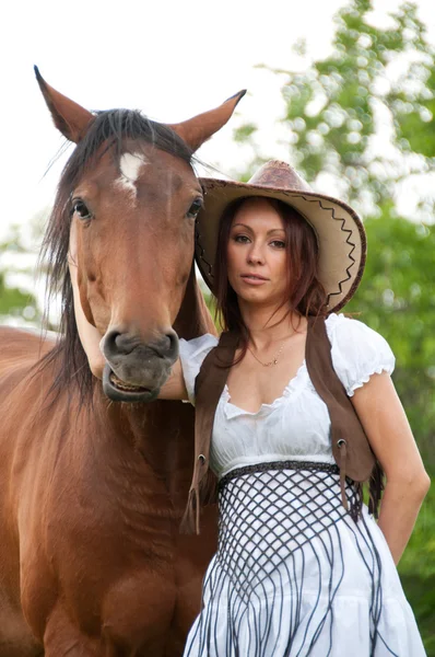En vacker flicka i en cowboy hatt med en häst — Stockfoto