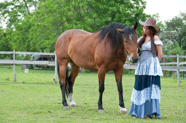 Una bella ragazza in un cappello da cowboy con un cavallo — Foto Stock