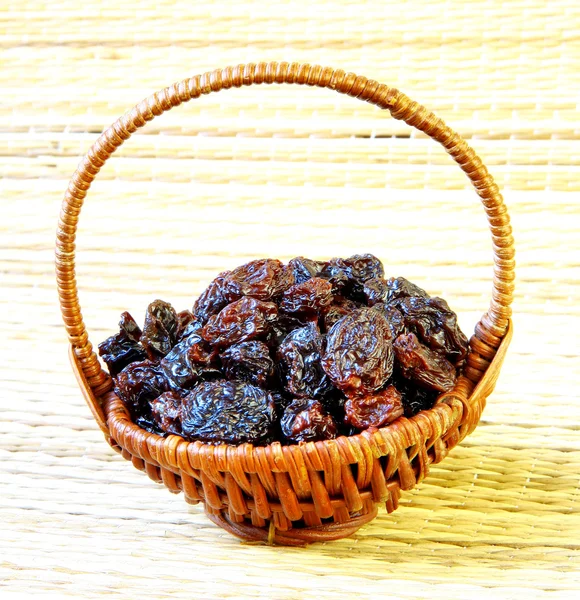 Black raisin in wicker basket on matting sunlight background — Stock Photo, Image