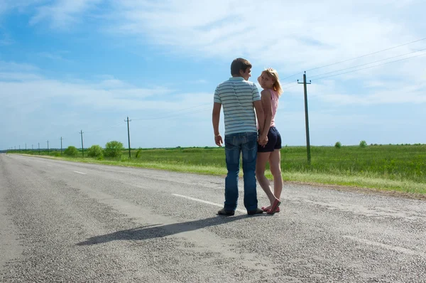 The young couple costs on the road — Stockfoto