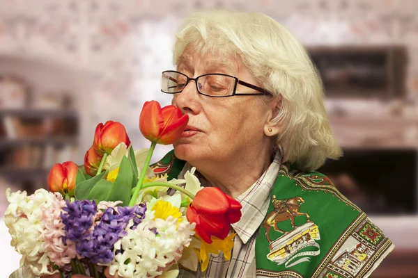 stock image Grandmother with flowers on a blurry room background