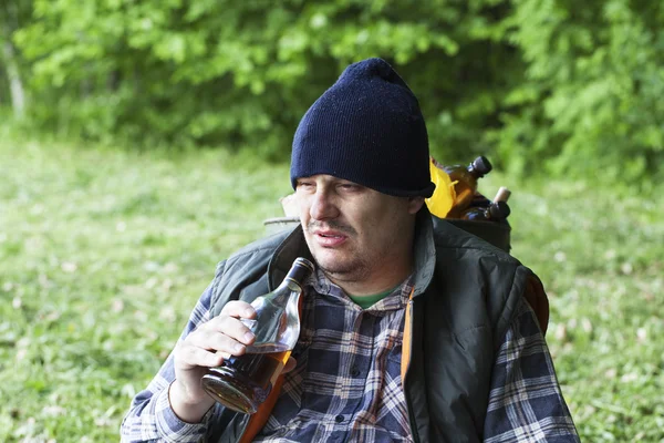 Tramp sitting in the park and drinking alcohol — Stock Photo, Image