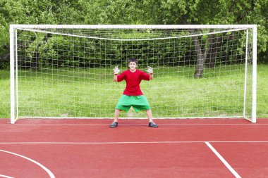 Boy standing in football goal clipart