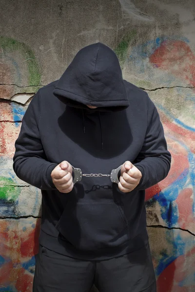 Человек в наручниках на фоне стены — стоковое фото