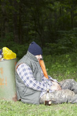 Homeless leaning against the garbage bins clipart