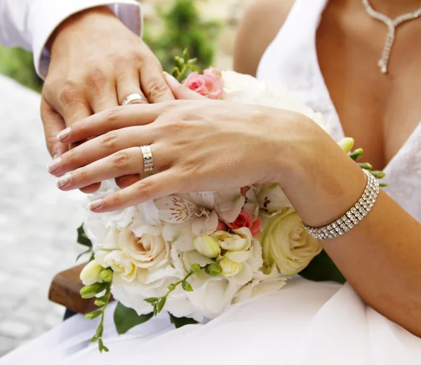 Χέρια και δαχτυλίδια σε γαμήλια ανθοδέσμη — Φωτογραφία Αρχείου
